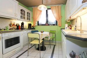 cocina con paredes verdes, mesa y sillas en Apartment Goehrenz, Markranstadt, en Markranstädt
