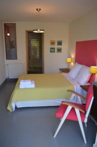 - une chambre avec un grand lit et une chaise rouge dans l'établissement Le Jardin Secret, à Gauriac