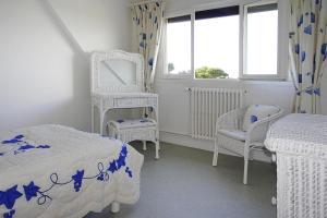 a bedroom with two beds and two chairs and a window at Holiday home with sea views, Trebeurden in Trébeurden