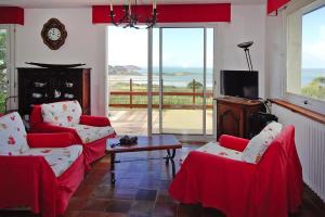 a living room with two red chairs and a tv at Holiday home with sea views, Trebeurden in Trébeurden