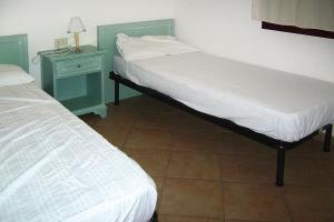 um quarto com 2 camas e uma mesa de cabeceira com um candeeiro em Residence La Tartaruga Monte Petruso San Teodoro em San Teodoro