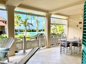une terrasse couverte avec une table et des chaises et une vue sur la piscine dans l'établissement La Dolce Vita Beachfront Apt 2, à Las Terrenas