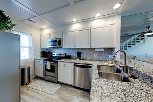 a kitchen with white cabinets and stainless steel appliances at Oceanfront Townhouse in Carolina Beach