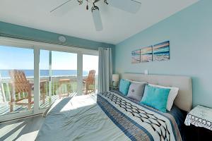a bedroom with a bed and a balcony with the ocean at Oceanfront Townhouse in Carolina Beach