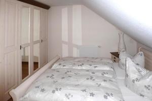 um quarto com uma cama branca e lençóis floridos em Apartment Landhaus Markus, Süderschwei em Süderschwei