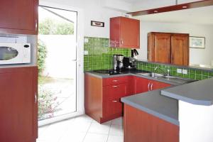 eine Küche mit roten Schränken und einer Mikrowelle in der Unterkunft Holiday Home St- Gildas-de-Rhuys - BRE04131-F in Saint-Gildas-de-Rhuys