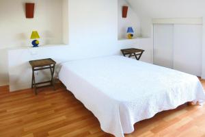 ein weißes Schlafzimmer mit einem weißen Bett und 2 Tischen in der Unterkunft Holiday Home St- Gildas-de-Rhuys - BRE04131-F in Saint-Gildas-de-Rhuys
