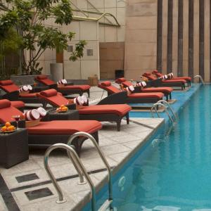 eine Reihe von roten Liegestühlen neben einem Pool in der Unterkunft Radisson Blu Hotel, Nagpur in Nagpur
