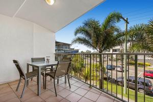 a patio area with chairs, a table and a balcony at Surfcomber on the Beach in Maroochydore