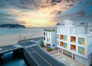 a building next to a beach with the ocean at HOTEL AO KAMAKURA in Kamakura