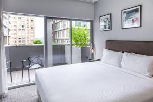 1 dormitorio con 1 cama blanca grande y balcón en Holiday Inn & Suites Sydney Bondi Junction, an IHG Hotel, en Sídney