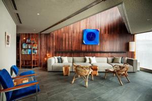 a living room with a couch and chairs and a tv at HOTEL AO KAMAKURA in Kamakura