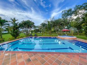 une grande piscine avec un patio en briques et des palmiers dans l'établissement Finca Turística Villa Natasha - Casa Campestre y Cabañas Villavicencio, à Villavicencio