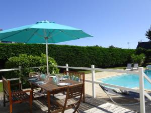 stół z parasolem obok basenu w obiekcie Holiday home with private outdoor pool, Gouesnac"h w mieście Gouesnach