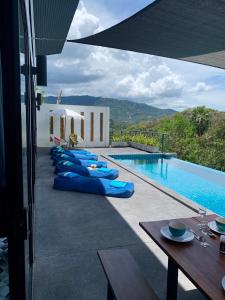 a swimming pool with blue pillows next to a building at Sky Villas Philippa with Free Car in Laem Set Beach