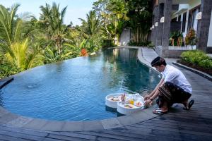 a man kneeling in front of a swimming pool at Yanyan Resort Ubud in Ubud