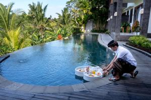 a man kneeling in front of a swimming pool at Yanyan Resort Ubud in Ubud