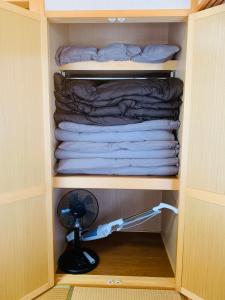 a closet with a fan and a pile of towels at ゆくい家 in Ginowan