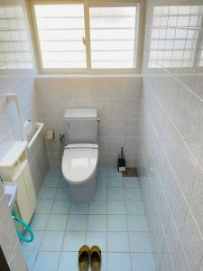 a bathroom with a toilet and two shoes on the floor at ゆくい家 in Ginowan +14 photos