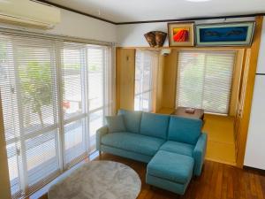 a living room with a blue couch and some windows at ゆくい家 in Ginowan