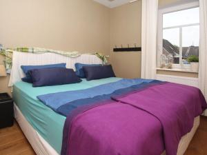 um quarto com uma cama grande com lençóis azuis e roxos em Apartment Alte Liebe, Dornumersiel em Dornumersiel