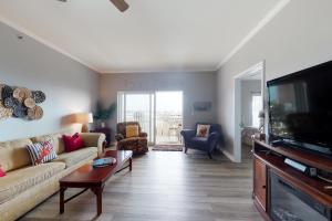 a living room with a couch and a flat screen tv at Waterside Village 406 - Isle of View More in Mexico Beach