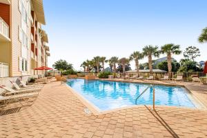 a swimming pool at a resort with chairs and palm trees at Waterside Village 406 - Isle of View More in Mexico Beach