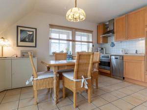 a kitchen with a wooden table and chairs and a chandelier at Apartment in St Peter-Ording in Süderhöft