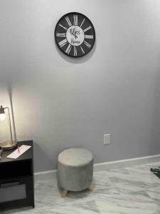 eine Uhr an einer Wand mit einem Stuhl in einem Zimmer in der Unterkunft The little Paris suite in Tampa