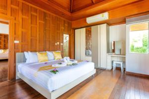 a bedroom with a large white bed with wooden walls at Oriental Thai Villa in Koh Samui 