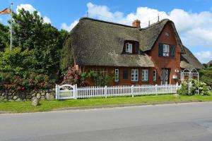 a house with a thatched roof and a white fence at Apartment, Oevenum in Oevenum