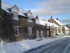 eine Reihe von Häusern im Schnee auf einer Straße in der Unterkunft Ellerby Country Inn in Ellerby