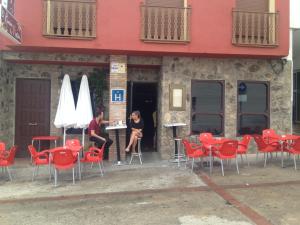a man and a woman sitting at a table with red chairs at Café Bar Hotel Jefi in Jaraiz de la Vera