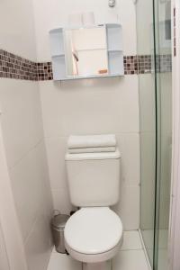 uma casa de banho com um WC e uma cabina de duche em vidro. em Hotel Morada do Mar no Guarujá