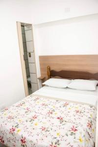 a bedroom with a bed with a floral bedspread at Hotel Morada do Mar in Guarujá