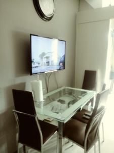 a glass table with chairs and a television on a wall at MOA Rental in Manila