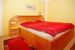 a bedroom with a wooden bed with a red blanket at Cottage, Zinnowitz in Zinnowitz