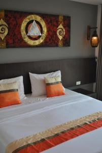 a bed with orange and white pillows on it at Baan Kata Maytha in Kata Beach