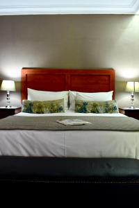 a large bed with a wooden headboard and pillows at 50 ON GREEFF in Lichtenburg +39 photos