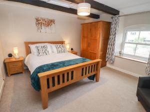 ein Schlafzimmer mit einem Holzbett und einem Fenster in der Unterkunft The Cottage in Tetbury