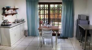 a kitchen with a table and a window with blue curtains at Green Scape Flatlet in Pretoria