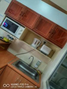 a kitchen with a sink and a microwave at Apartment Teluk Batik in Lumut
