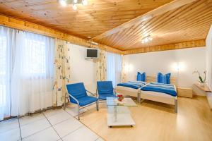 Pokój z łóżkiem i 2 niebieskimi krzesłami w obiekcie Pension Aaron am See w mieście Grächen