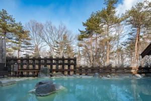 un bassin d'eau avec des rochers et des arbres dans l'établissement Konoha, à Kusatsu