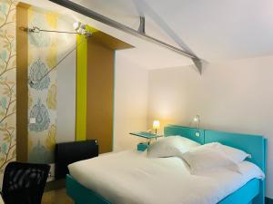 a bedroom with a blue and white bed with two chairs at Hôtel Le Dormeur du Val in Charleville-Mézières +78 photos