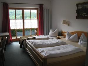two beds in a hotel room with a window at Alpenhotel Allgäu in Hohenschwangau