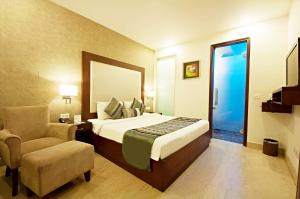 - une chambre avec un lit, une chaise et un miroir dans l'établissement The Grand Vikalp By Saga Hotels, à New Delhi