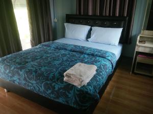 een bed met een blauwe deken en een handdoek erop bij ต้งโฮมหละปูน in Lamphun