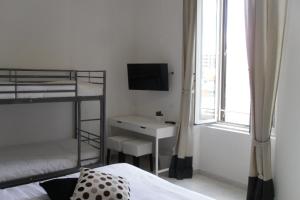 a bedroom with bunk beds and a desk and a television at 5 Rooms Affittacamere in Civitavecchia