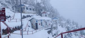 a group of buildings in the snow on a mountain at Dev Bhoomi Resort in Kanatal